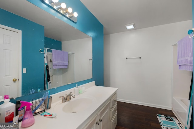 bathroom with wood finished floors, visible vents, vanity, baseboards, and a bath