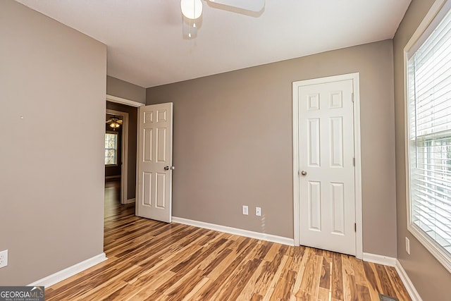 unfurnished bedroom with a ceiling fan, baseboards, and wood finished floors