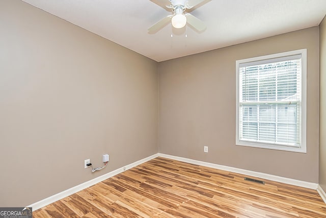 unfurnished room with light wood finished floors, visible vents, and baseboards