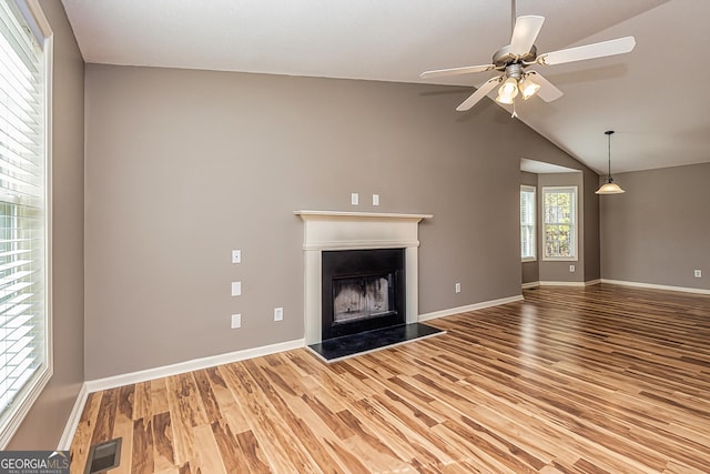 unfurnished living room with a fireplace with raised hearth, wood finished floors, visible vents, and baseboards