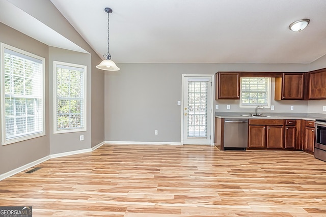 kitchen featuring lofted ceiling, a sink, light countertops, appliances with stainless steel finishes, and pendant lighting