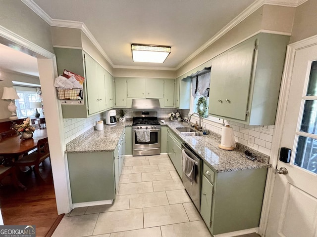 kitchen with tasteful backsplash, appliances with stainless steel finishes, light stone counters, crown molding, and a sink