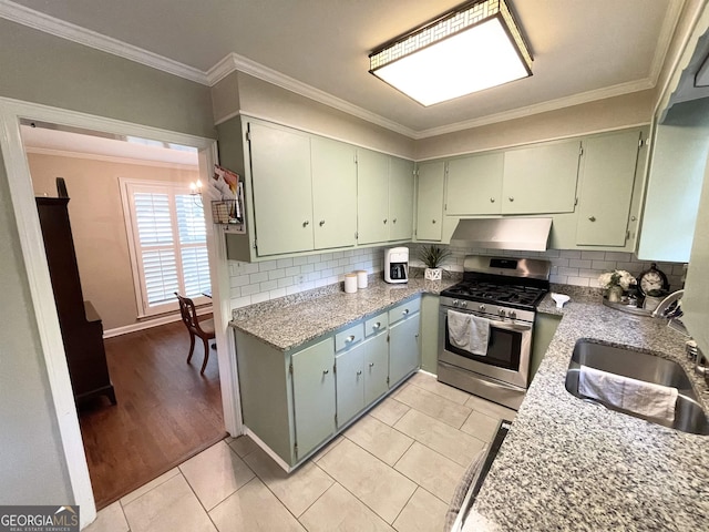 kitchen with under cabinet range hood, a sink, stainless steel range with gas cooktop, tasteful backsplash, and crown molding