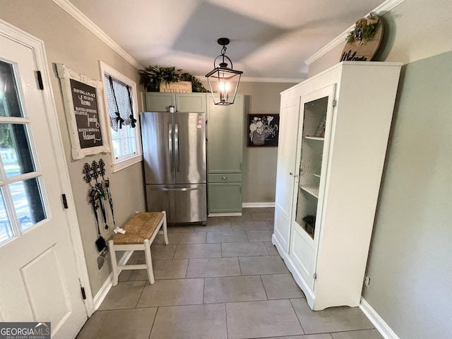 kitchen featuring baseboards, freestanding refrigerator, crown molding, pendant lighting, and light tile patterned flooring