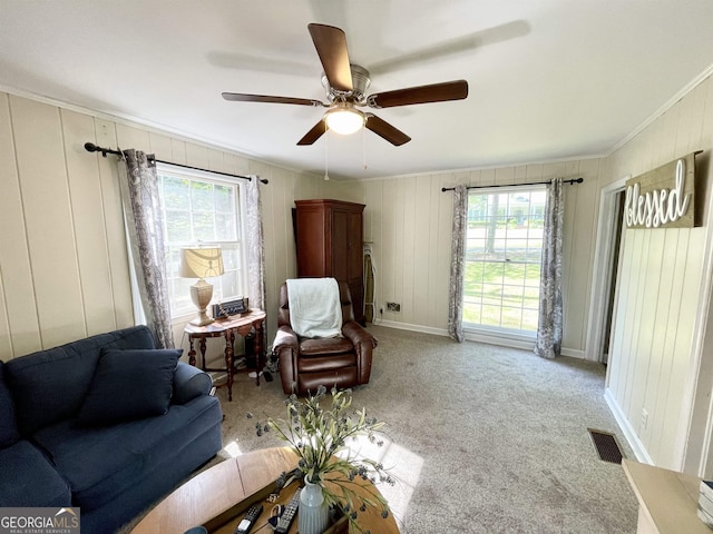 sitting room featuring crown molding, light colored carpet, visible vents, a ceiling fan, and baseboards