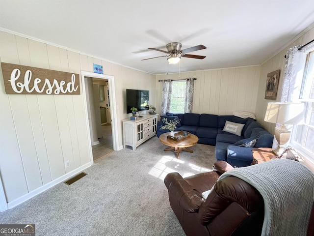 living room featuring a ceiling fan, light colored carpet, visible vents, and ornamental molding