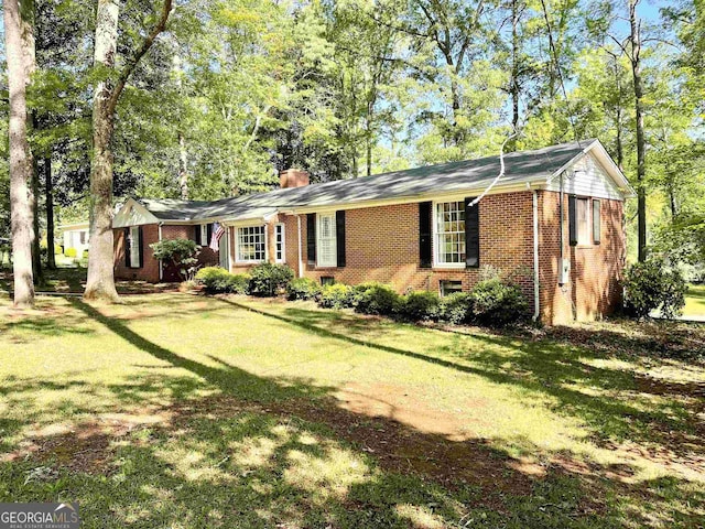 ranch-style home with brick siding, a chimney, and a front lawn