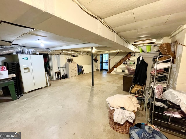 unfinished basement featuring white refrigerator with ice dispenser and stairway