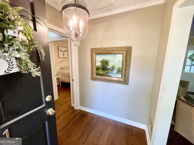 hall featuring baseboards, a notable chandelier, ornamental molding, and dark wood-type flooring