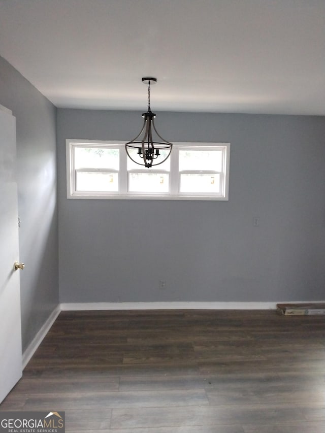 unfurnished dining area featuring an inviting chandelier, baseboards, and dark wood-style flooring