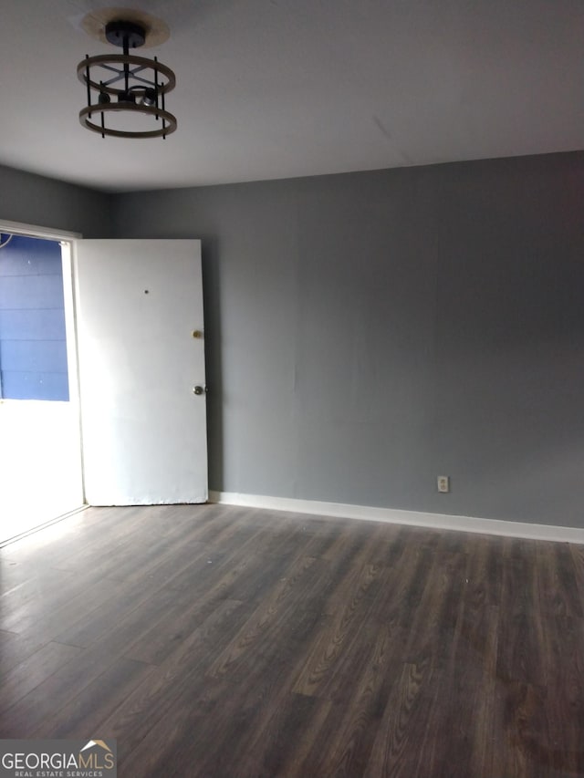 unfurnished room featuring dark wood-style floors and baseboards