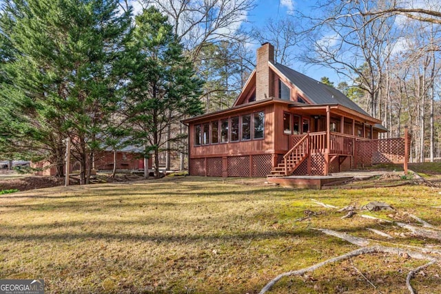 view of side of home with a chimney, stairway, and a yard