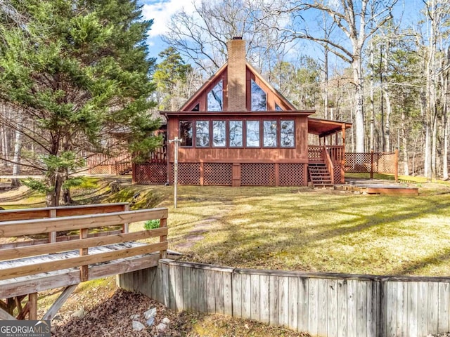 back of house featuring a yard, a chimney, stairway, a sunroom, and a deck