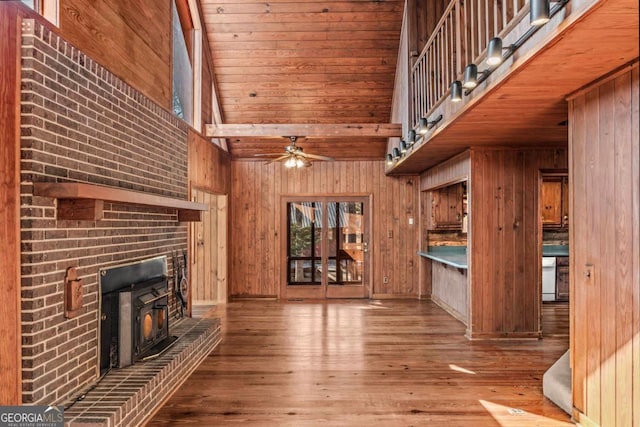 unfurnished living room featuring light wood-style flooring, wood walls, and a towering ceiling