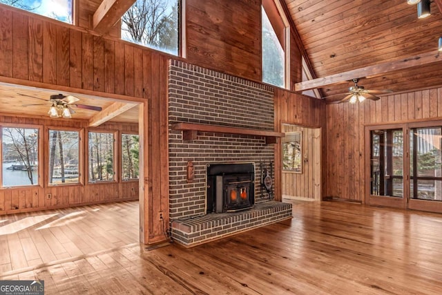 unfurnished living room featuring wood walls, wood finished floors, and a healthy amount of sunlight