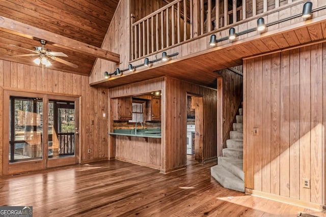 kitchen with wood walls, wood finished floors, high vaulted ceiling, wooden ceiling, and range