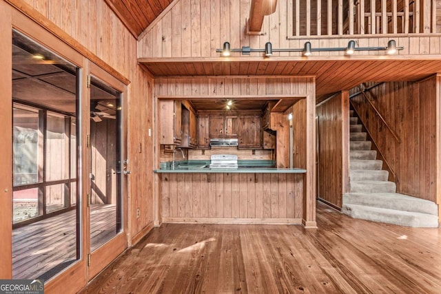 kitchen with range hood, white electric range oven, wooden walls, wood finished floors, and a peninsula