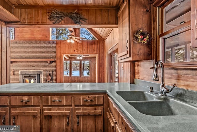 kitchen featuring brown cabinets, lofted ceiling, a sink, wooden walls, and wooden ceiling