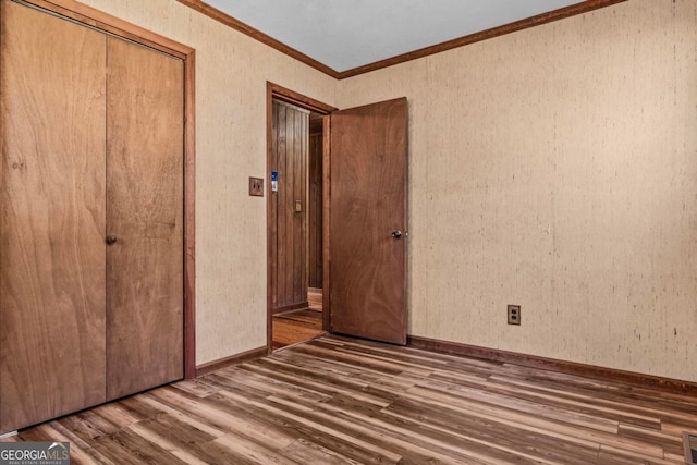 unfurnished bedroom with visible vents, baseboards, ornamental molding, a closet, and dark wood finished floors