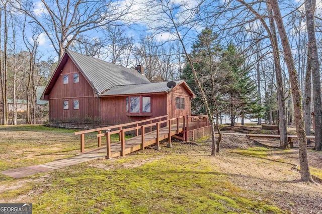 view of side of home with a lawn, a chimney, and a wooden deck