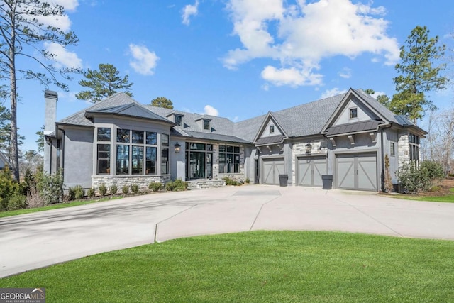 view of front of house with concrete driveway, stone siding, metal roof, a standing seam roof, and a front yard