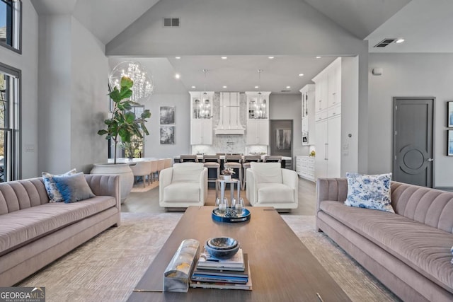 living area with a chandelier, high vaulted ceiling, and visible vents