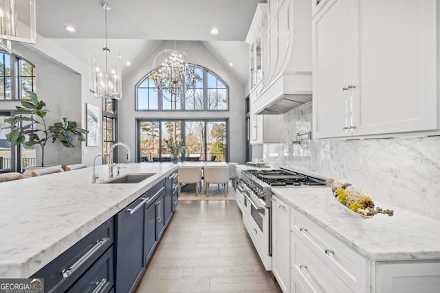 kitchen with range with two ovens, white cabinets, a sink, and an island with sink