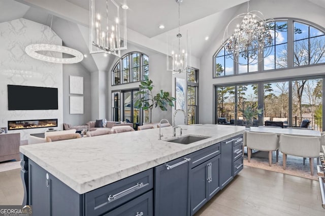 kitchen featuring blue cabinets, a sink, a center island with sink, and a premium fireplace