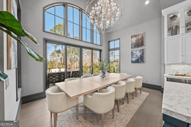 dining room featuring a chandelier, a high ceiling, plenty of natural light, and light wood finished floors