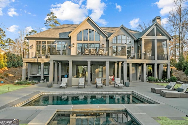 back of house featuring an outdoor pool, a patio, a balcony, an in ground hot tub, and stucco siding