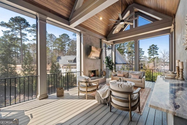 sunroom featuring lofted ceiling, a large fireplace, wood ceiling, and a ceiling fan