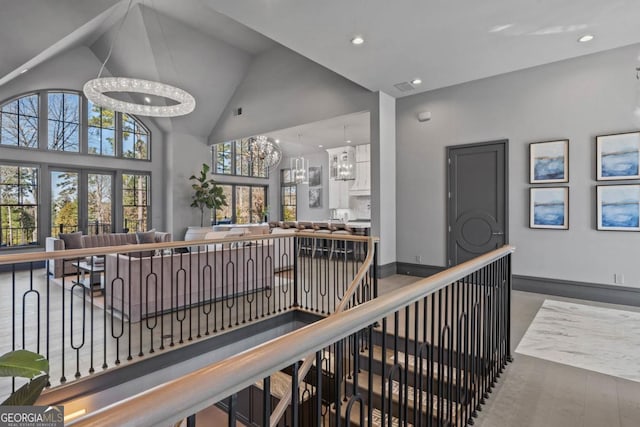 corridor featuring an inviting chandelier, an upstairs landing, wood finished floors, high vaulted ceiling, and baseboards