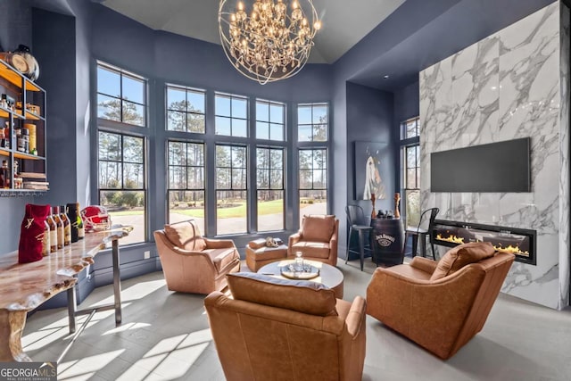 interior space with plenty of natural light, a high ceiling, a chandelier, and a high end fireplace