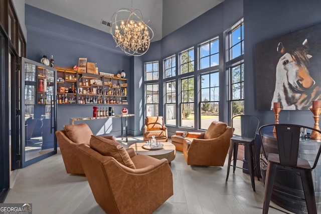 sitting room with visible vents, a towering ceiling, a dry bar, and an inviting chandelier