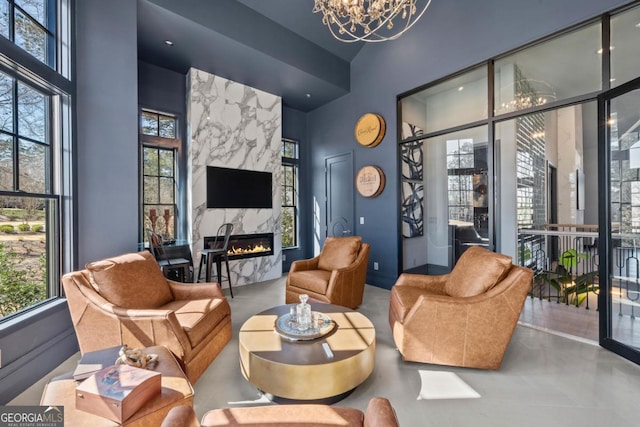 sitting room featuring a premium fireplace, a high ceiling, and a notable chandelier