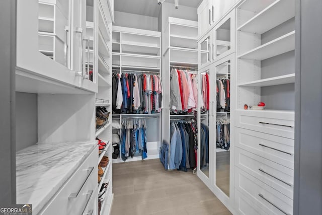 walk in closet with light wood-style floors