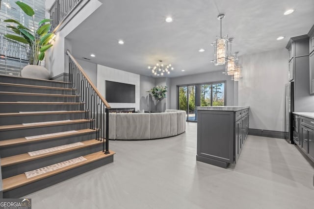 interior space with high quality fridge, a notable chandelier, gray cabinetry, open floor plan, and light countertops