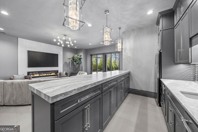 kitchen featuring light stone counters, recessed lighting, a fireplace, open floor plan, and pendant lighting