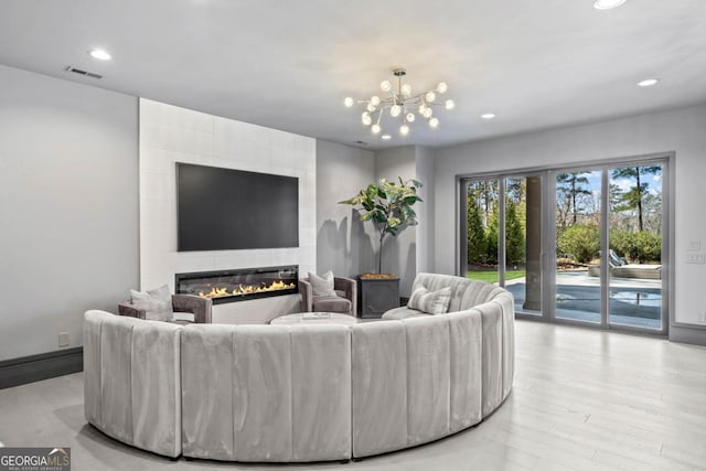 living area featuring recessed lighting, visible vents, light wood-style floors, a large fireplace, and a chandelier