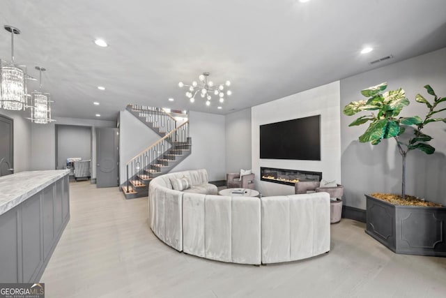 living room featuring visible vents, a glass covered fireplace, stairway, an inviting chandelier, and recessed lighting