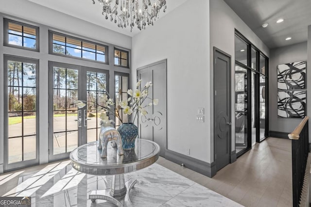 foyer entrance featuring a notable chandelier, recessed lighting, wood finished floors, baseboards, and french doors