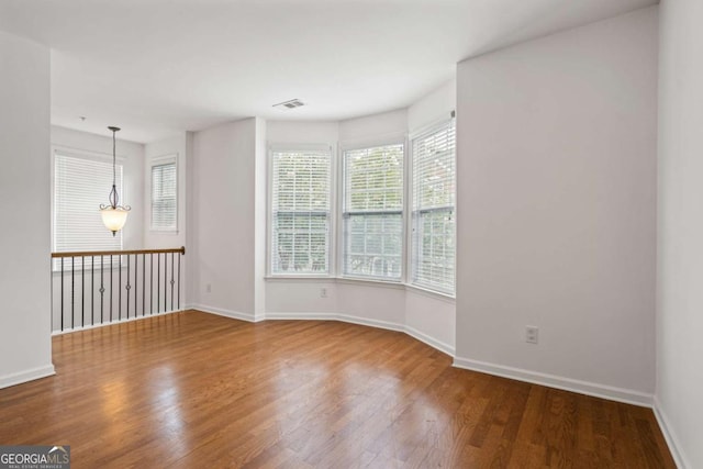 empty room featuring baseboards, visible vents, and wood finished floors