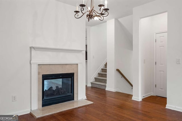 unfurnished living room featuring dark wood-style floors, a high end fireplace, stairway, and baseboards