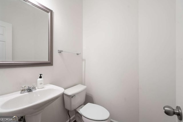 bathroom featuring a sink, toilet, and baseboards