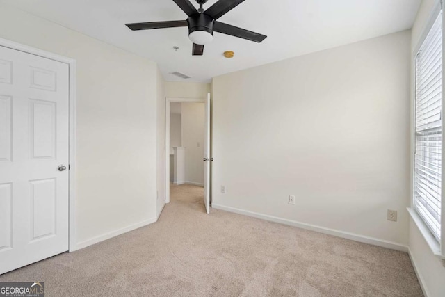 unfurnished bedroom featuring light colored carpet, ceiling fan, visible vents, and baseboards