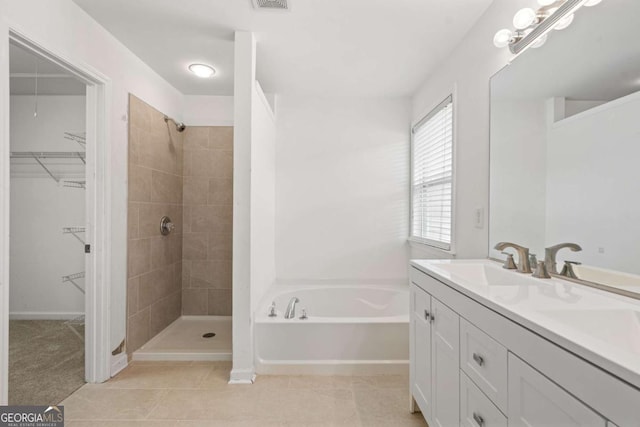 full bath with tile patterned floors, a garden tub, a spacious closet, a shower stall, and a sink