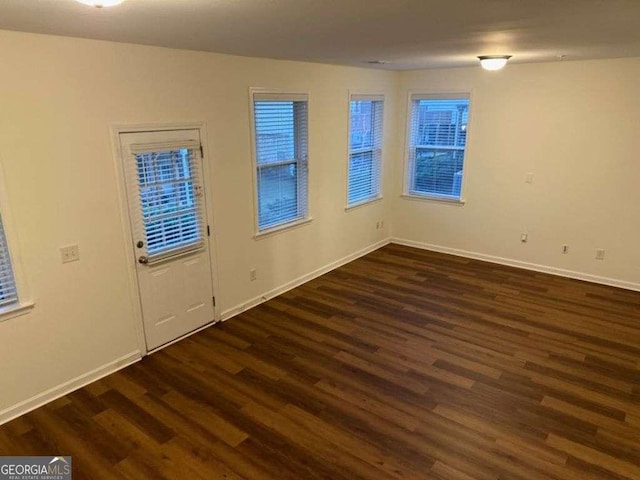 spare room with dark wood-style floors and baseboards