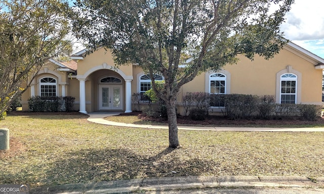 view of front facade with a front lawn, french doors, and stucco siding