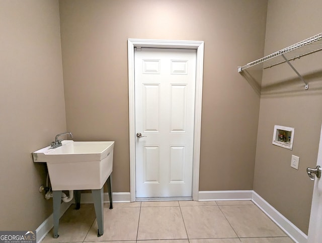 clothes washing area featuring light tile patterned floors, laundry area, washer hookup, and baseboards