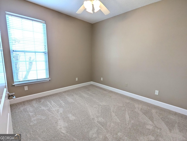 carpeted empty room with a ceiling fan and baseboards